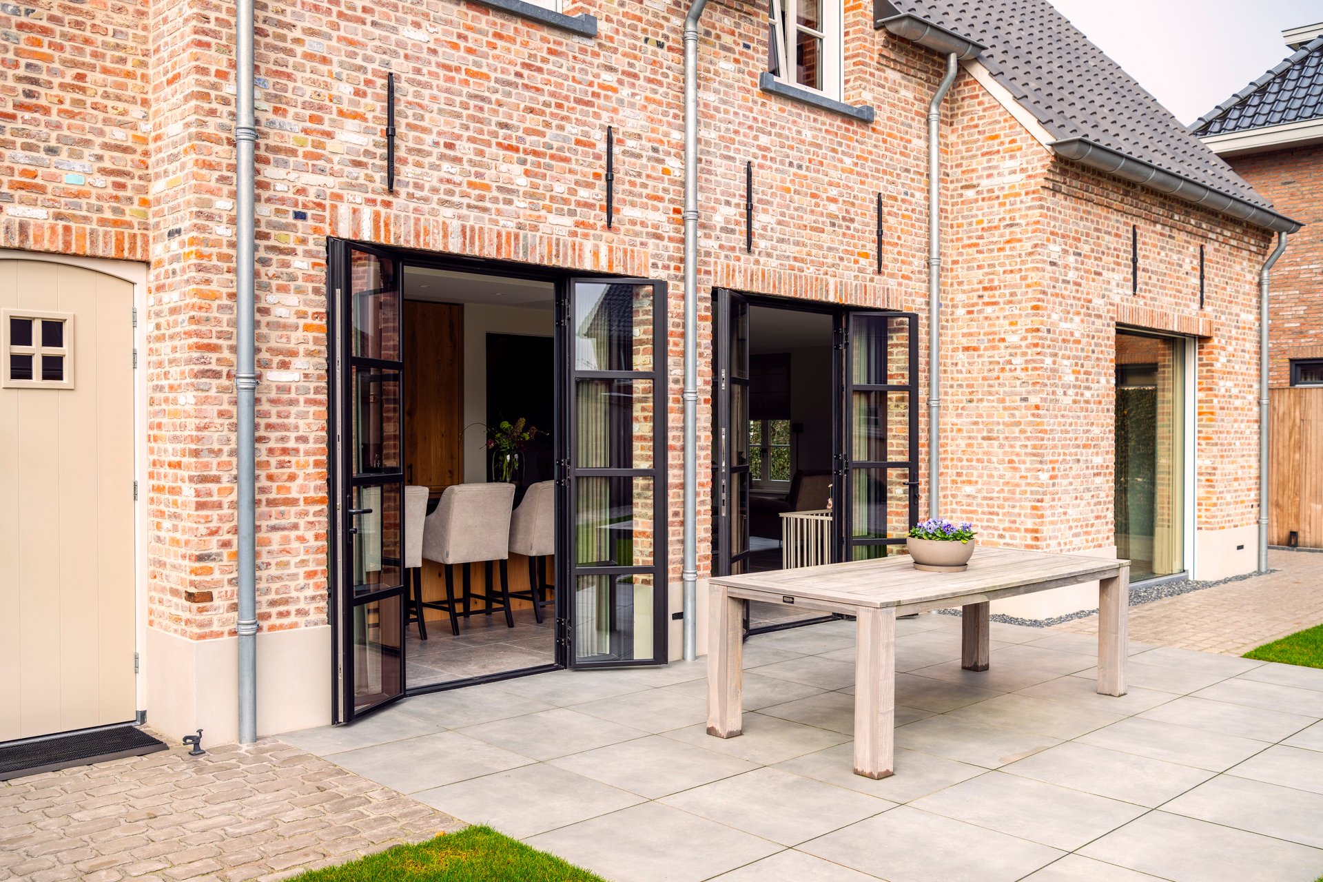 Achtergevel van dichtbij kempische nieuwbouwwoning Kesteren met twee sets stalen buitendeuren Toronto deuren geopend